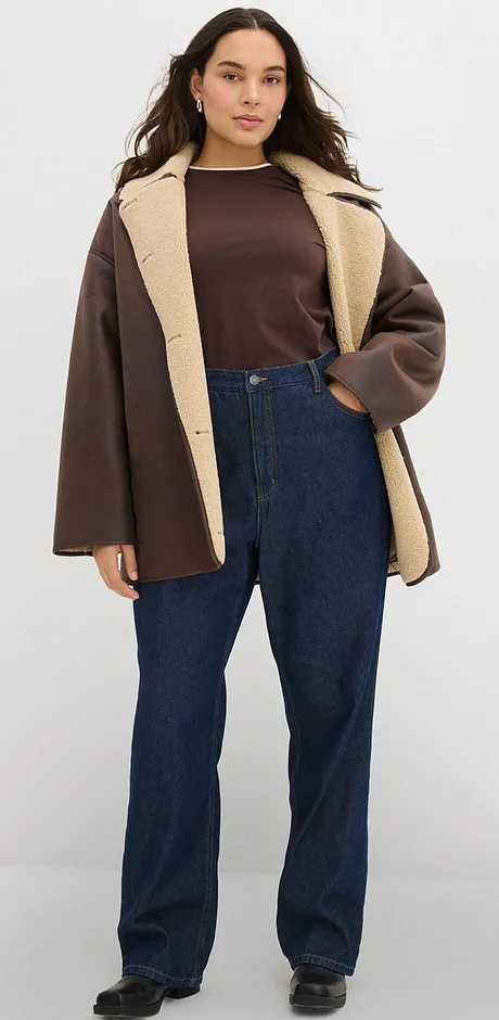 Brun jacka med ljus krage, passande mörk topp och jeans.