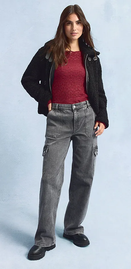 Svart jacka, röd topp, vida, gråa jeans och mörka skor.