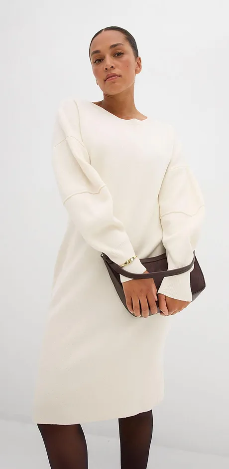 En cremefärgad, långärmad klänning med rund halsringning.

