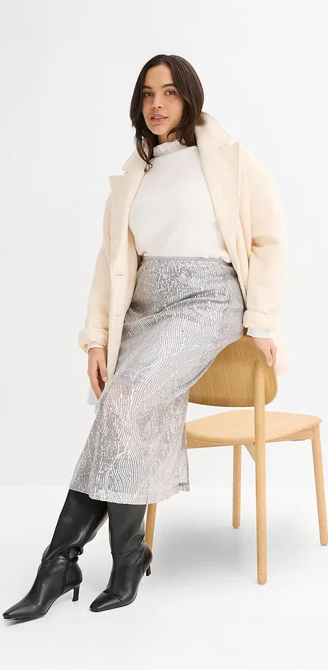 Cremefärgad kappa, vit polotröja, silverfärgad kjol och svarta läderstövlar.

