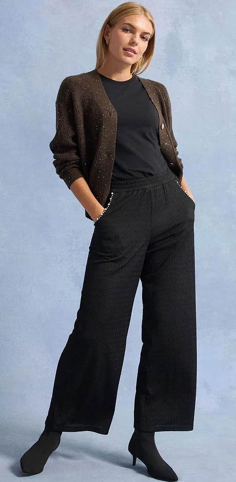 Svarta byxor, T-shirt och glittrig kofta.

