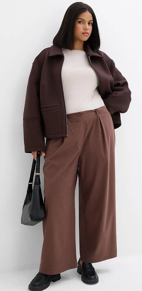 Brun jacka, vit topp och vida byxor i jordnära toner.

