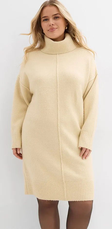 Krämvit stickad klänning med hög krage och långa ärmar.

