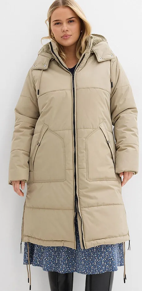 Beige täckkappa med huva över blå blommig klänning.

