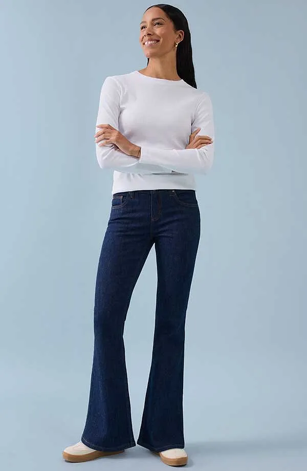 Vit l&aring;ng&auml;rmad topp kombinerad med m&ouml;rkbl&aring; utsv&auml;ngda byxor f&ouml;r en tidl&ouml;s och elegant look.