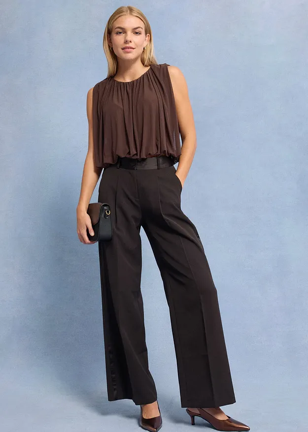 Brunt &auml;rml&ouml;st linne och vida, m&ouml;rka byxor.

