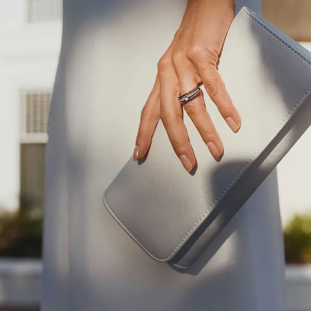 Vit kl&auml;nning kombinerad med en ljus clutch och skira ringsmycken.

