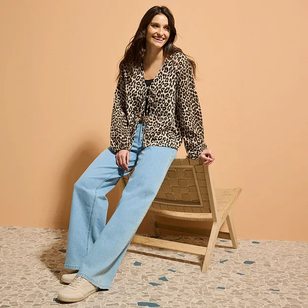 Blus med leopardm&ouml;nster m&ouml;ter ett par ljusbl&aring;, utsv&auml;ngda jeans.