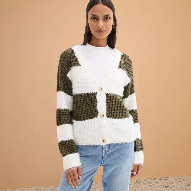 Stickad cardigan i vitt och olivgr&ouml;nt, kombinerad med ljusbl&aring; jeans.