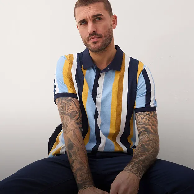 Randig pik&eacute;tr&ouml;ja i bl&aring;tt, gult och vitt. M&ouml;rka byxor.

 