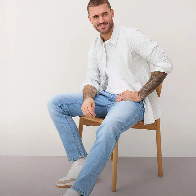 Ljus skjorta med r&auml;nder, bl&aring;a jeans och vita sneakers.

