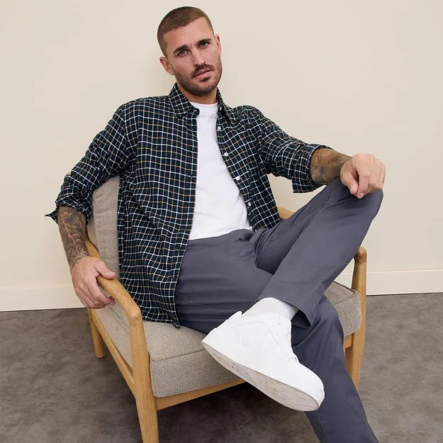 Rutig skjorta &ouml;ver vit T-shirt, gr&aring; byxor och vita sneakers.

