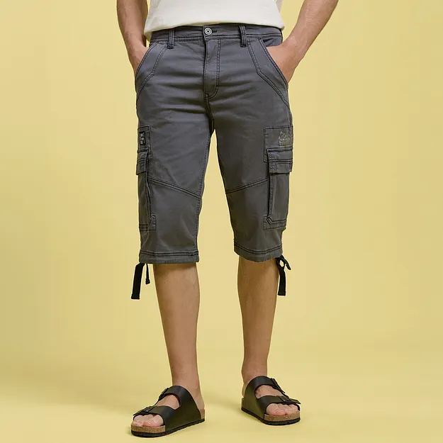 Gr&aring; cargoshorts med praktiska sidfickor, vit T-shirt och svarta sandaler.

