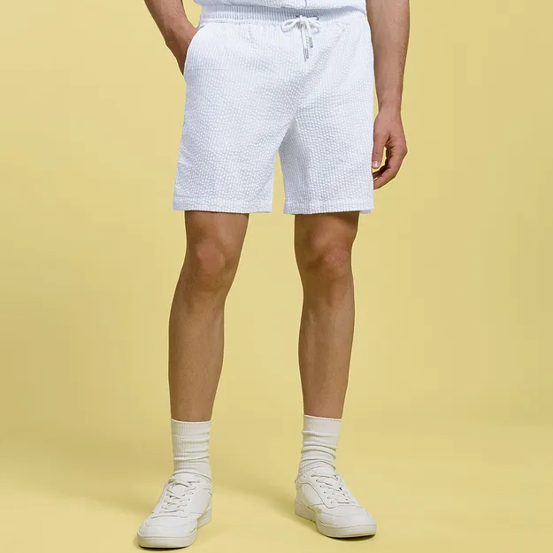 Vita shorts med dragsko, vita strumpor och sneakers.

