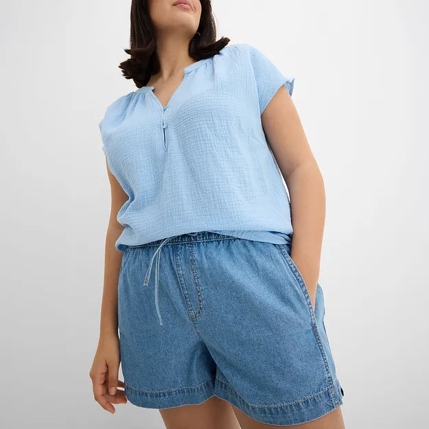 Ljusbl&aring; blus och l&ouml;sa jeansshorts i avslappnad sommarlook.

