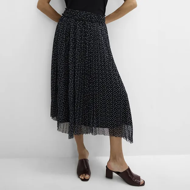 Stilrent, svart linne, prickig, plisserad kjol och eleganta, m&ouml;rkbruna sandaletter.
