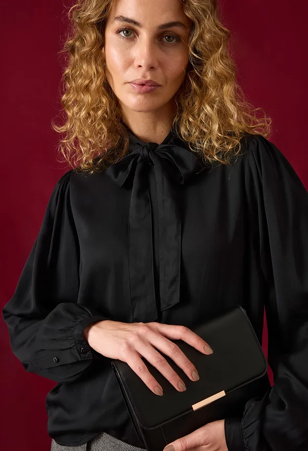 Svart blus med elegant knytband och vida &auml;rmar. Till det en chic kuvertv&auml;ska.