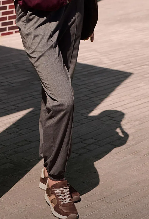 Gr&aring; tygbyxor och bruna sneakers f&ouml;r en ledig men elegant look.
