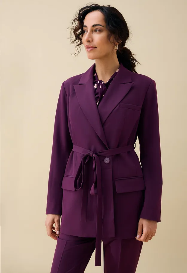 Elegant, violett kavaj med sk&auml;rp och matchande byxa, till det en prickig blus.