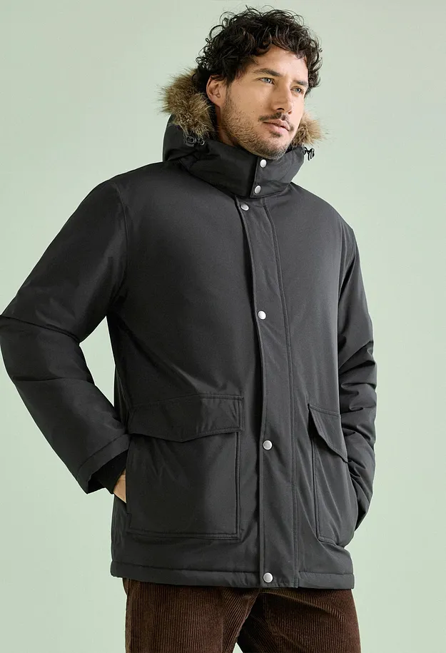 Mannen har p&aring; sig en svart parkas med fuskp&auml;lshuva