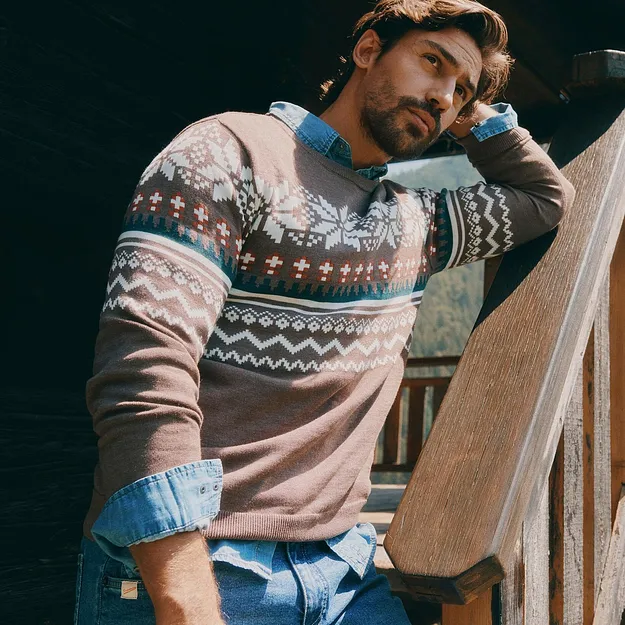 Mannen har p&aring; sig en m&ouml;nstrad tr&ouml;ja &ouml;ver en jeansskjorta och bl&aring;a jeans.