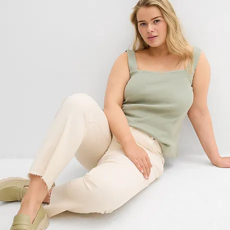 Grönt linne, ljusa jeans med fransiga fållar och pastellfärgade skor.