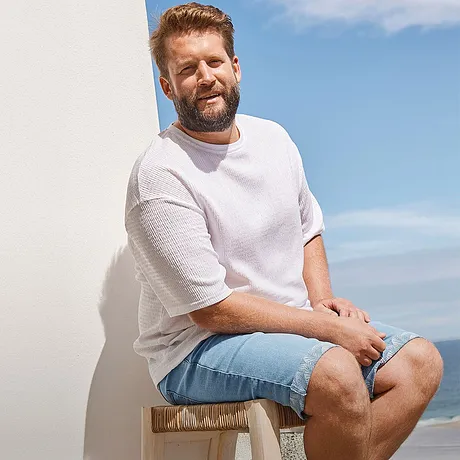 Avslappnad sommarlook: Vit T-shirt och ljusblå jeansshorts för en avslappnad dag på stranden.