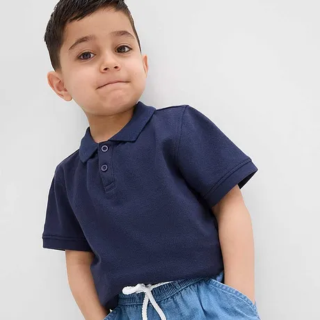 En mörkblå pikétröja kombinerad med ljusblå jeans.