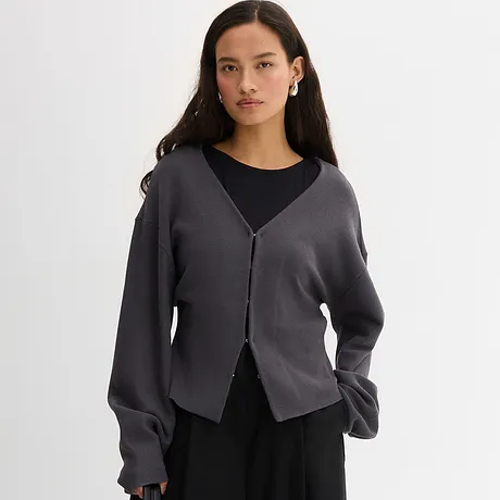 Elegant grå cardigan över ett svart linne. Ledig look med V-ringning och knappslå.