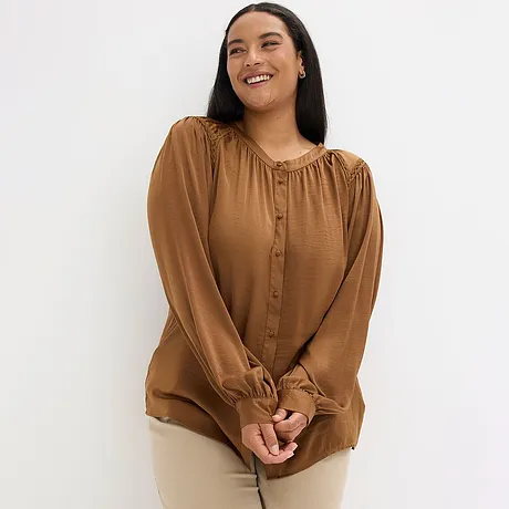 Brun blus med knappslå och rynkningar vid halsringningen.