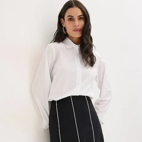 Vit blus med krage och svartvit kjol med vertikala ränder.

