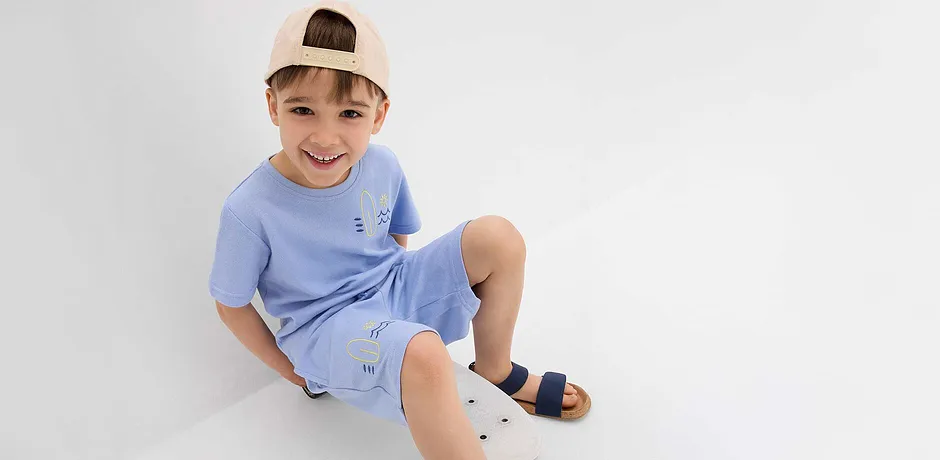 Ljusblå T-shirt och shorts med söta broderier, beige basebollkeps och mörkblå sandaler.