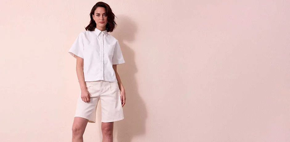 Somrig outfit i vitt: kortärmad denimblus med krage och knälånga shorts.