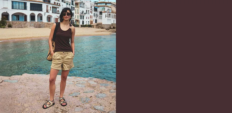 Kvinna i svart linne och beige shorts med sandaler.