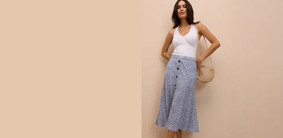 Vit ärmlös topp kombinerad med en mönstrad midikjol. Därtill en handväska i strålook för en snygg sommarlook.
