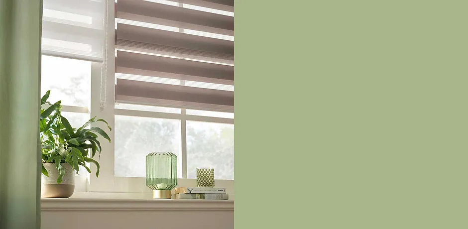 Gardiner i jordnära toner. Gröna dekorationer och krukväxter skapar en naturlig atmosfär.