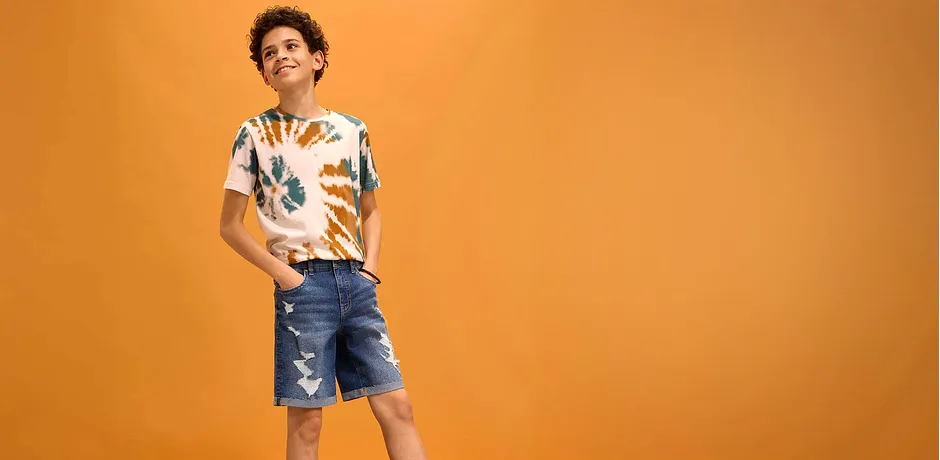 Somrig outfit med en färgglad skjorta och slitna jeansshorts.
