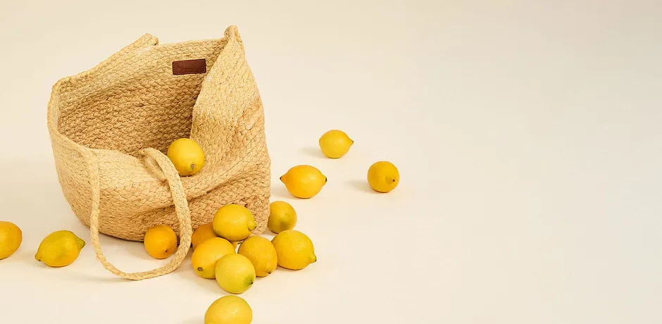 Väska i strålook med handtag, fylld med färska citroner.