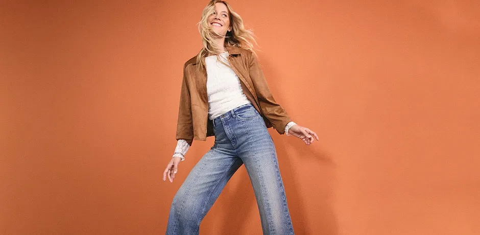 Avslappnad look: Brun skinnjacka, vit topp och vida jeans för en avslappnad stil.