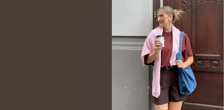 Somrig outfit med rosa cardigan, bruna shorts och blå väska.