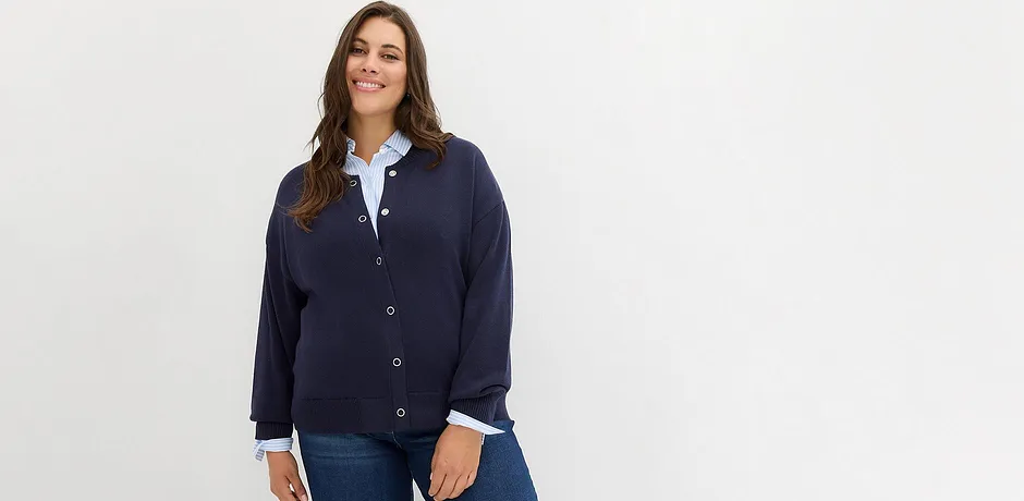 Mörkblå kofta över en vit blus, kombinerat med klassiska jeans.

