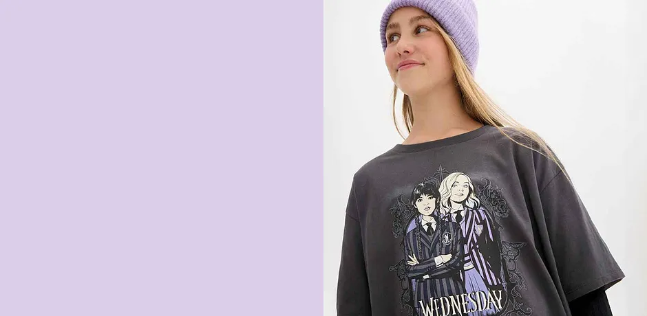 Lila mössa och grå oversized-T-shirt med mörkt gotiskt motiv präglar streetwear-looken.