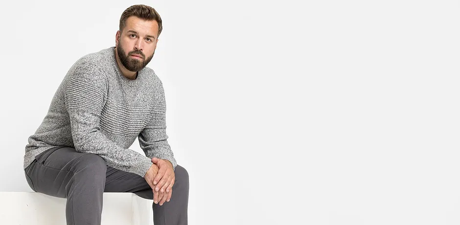 Grå stickad tröja och grå byxor bildar en avslappnad outfit.

