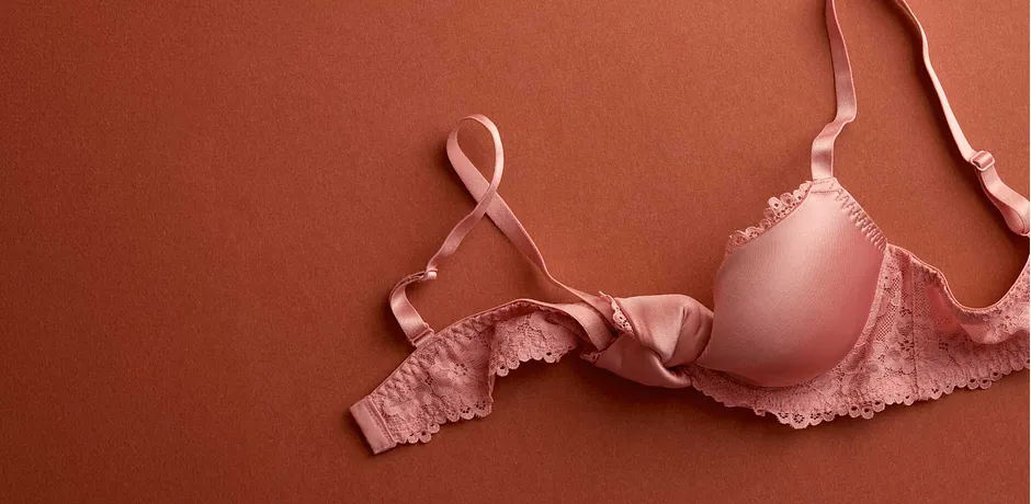 Ljusrosa BH med spetsdetaljer på terrakottafärgad bakgrund. Eleganta underkläder för kvinnor.