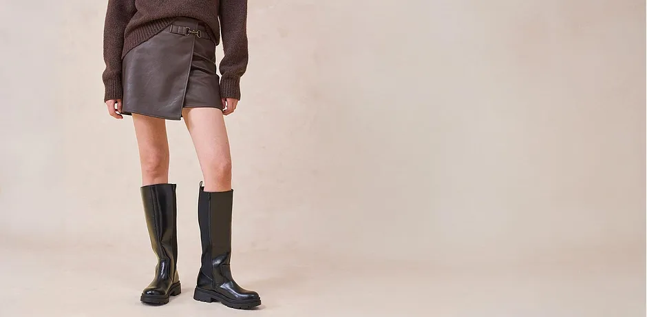 Läderkjol och knähöga stövlar kombinerat med en brun tröja.