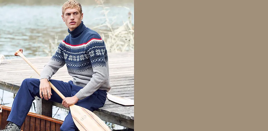 En mann i lusemönstrad tröja och jeans sitter lugnt på en båt.