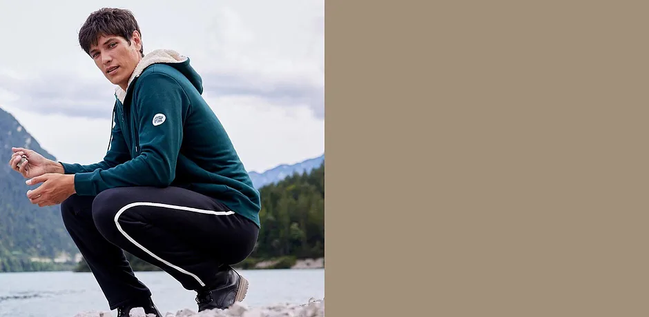 Grøn munkjacka och svart joggingbyxa för aktiva utomhusaktiviteter.