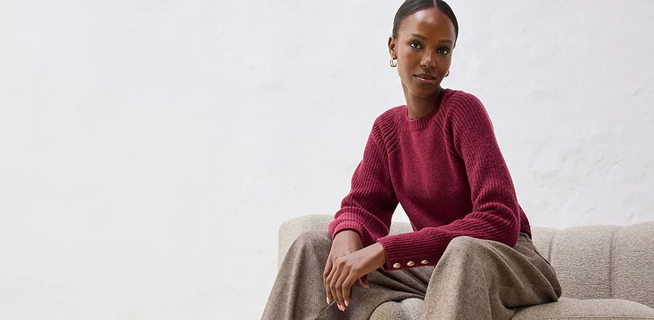 Röd tröja med beige byxa på ljus soffa.