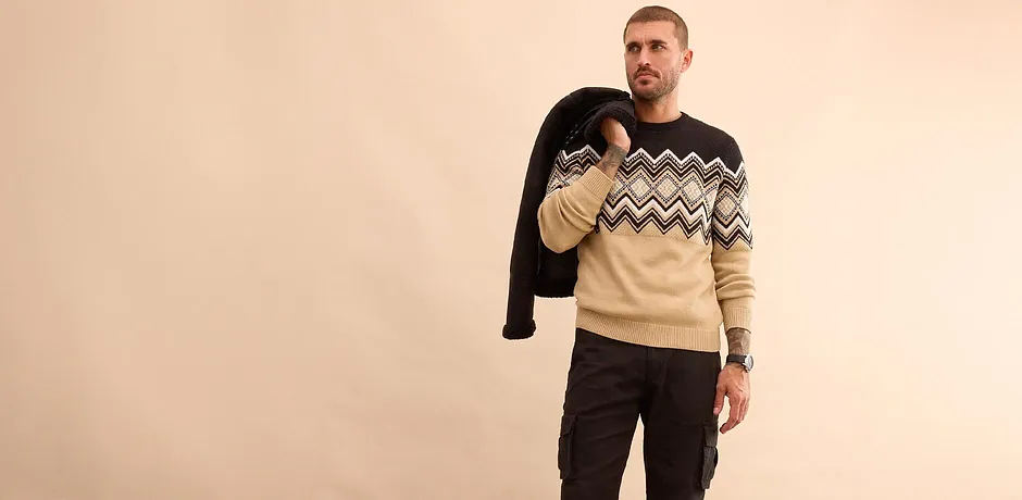 Stilfull look med svart vinterjacka, mönstrad tröja och jeans för kalla dagar.