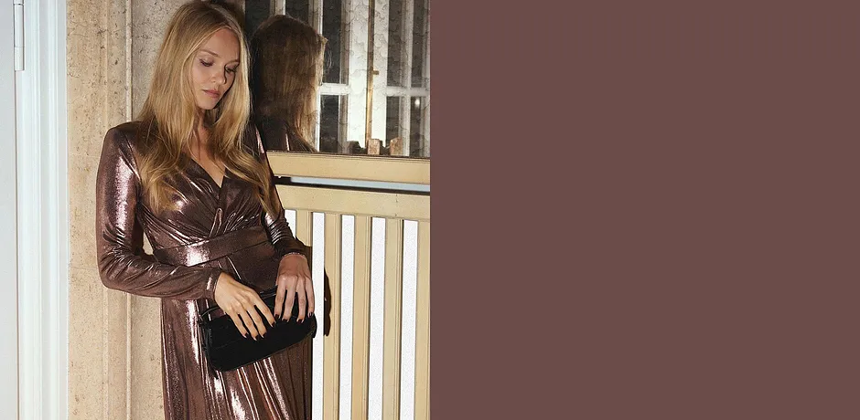 Glittrig klänning med V-ringning kombinerad med svart väska.